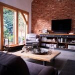 Interior Of Lounge With TV And Exposed Brick Walls In Modern Open Plan House Or Apartment