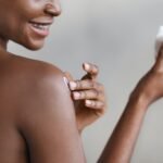 Unrecognizable african american woman applying skin butter on her shoulder