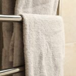 Modern heated towel rail on tiled bathroom wall