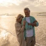 front view of active senior woman embracing senior woman on the beach at dusk