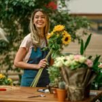 Florist standing and holding bouquet of sunflowers in flower shop