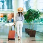 Young woman in hat with baggage in international airport