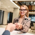 Young woman in hotel check in at reception or front office being given key card