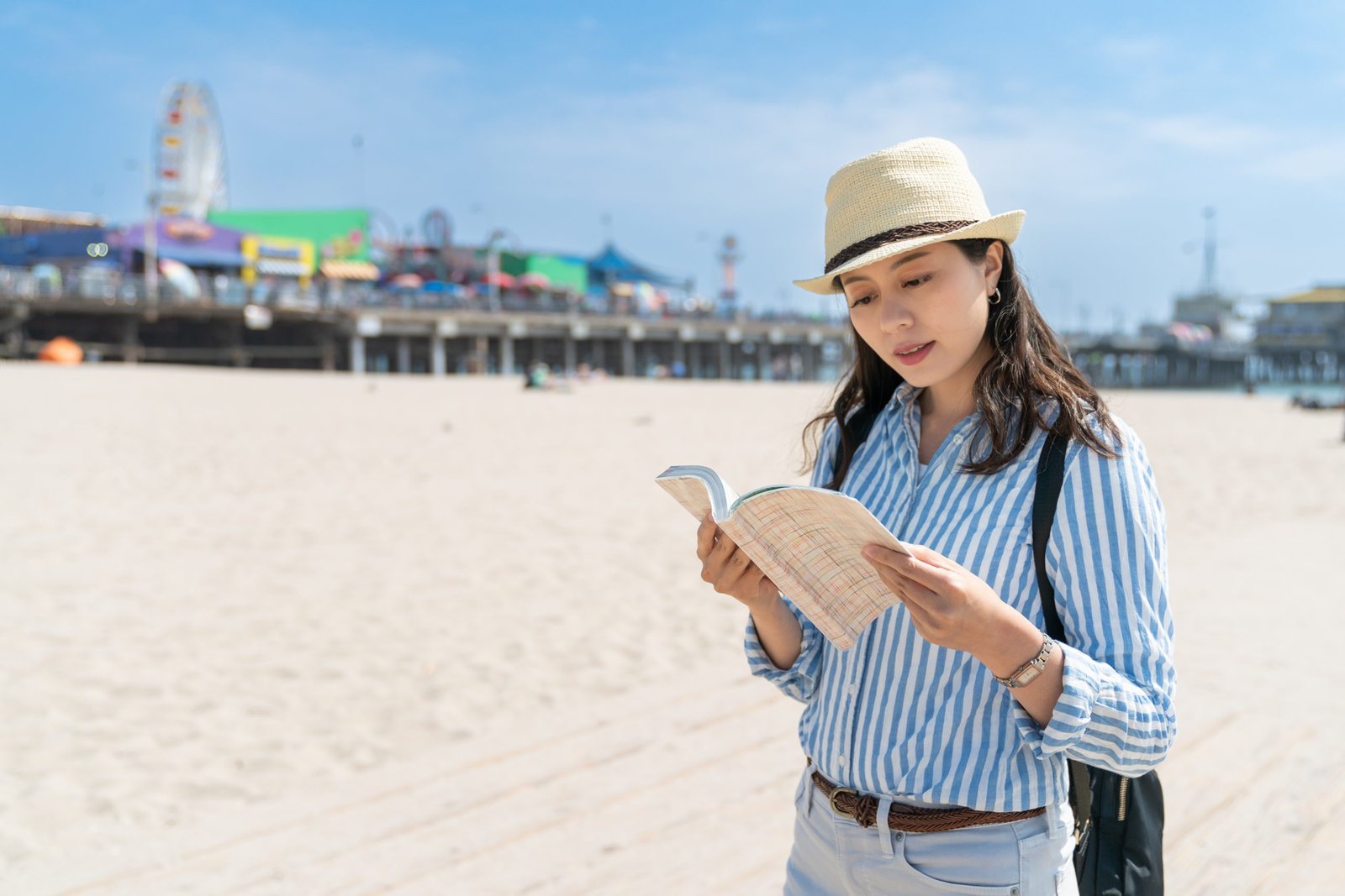 female using travel book on santa monica beach
