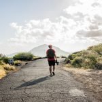 Young male tourist strolling with digital SLR on Makapuu coast path, Oahu, Hawaii, USA