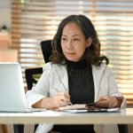 Focused middle aged woman entrepreneur reading online information on laptop.
