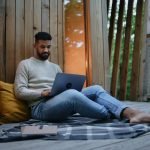 Man with laptop resting outdoors in a tree house, weekend away and remote office concept.