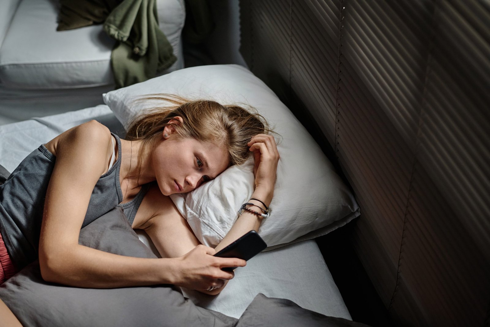 Above angle of anxious female teenager with smartphone looking at screen