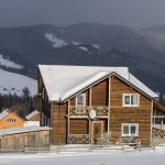 Home Weatherproofing winter landscape with wooden house in snowy mountains.