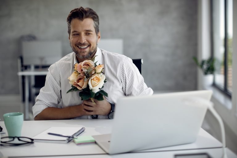 Happy businessman talking while having online date over laptop in the office.