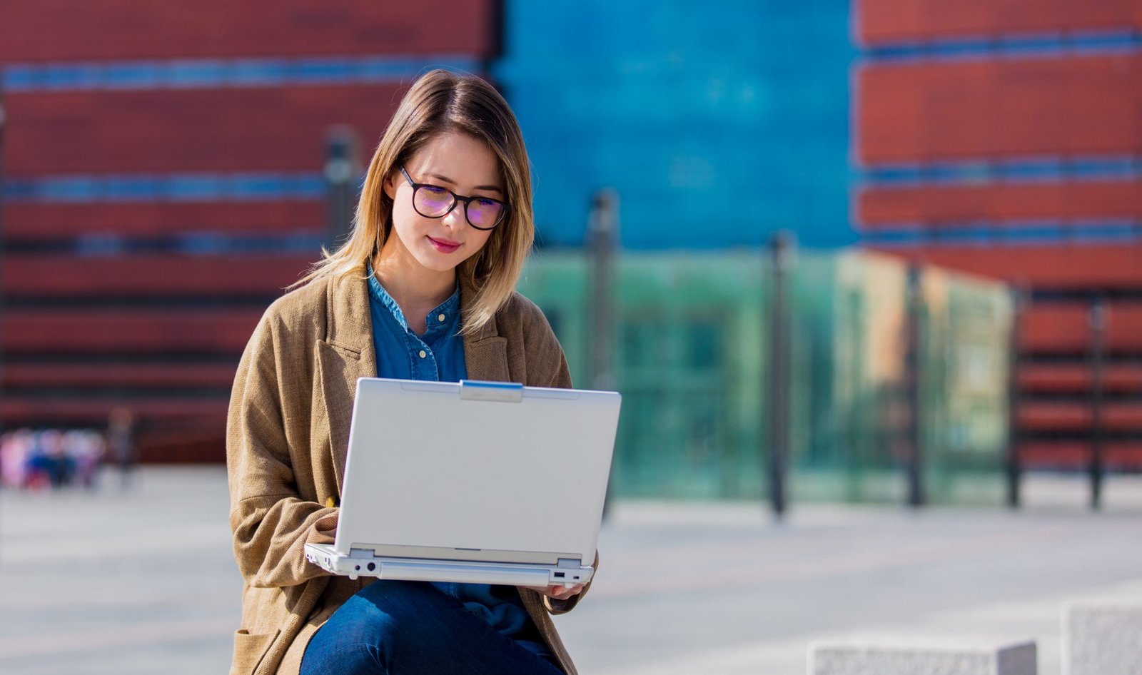Young businesswoman with laptop computer at urban outdoor.