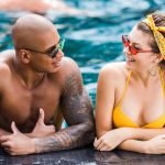 young in sunglasses looking at each other in swimming pool