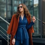 beautiful stylish woman walking in street stairs dressed in warm brown coat and blue suit