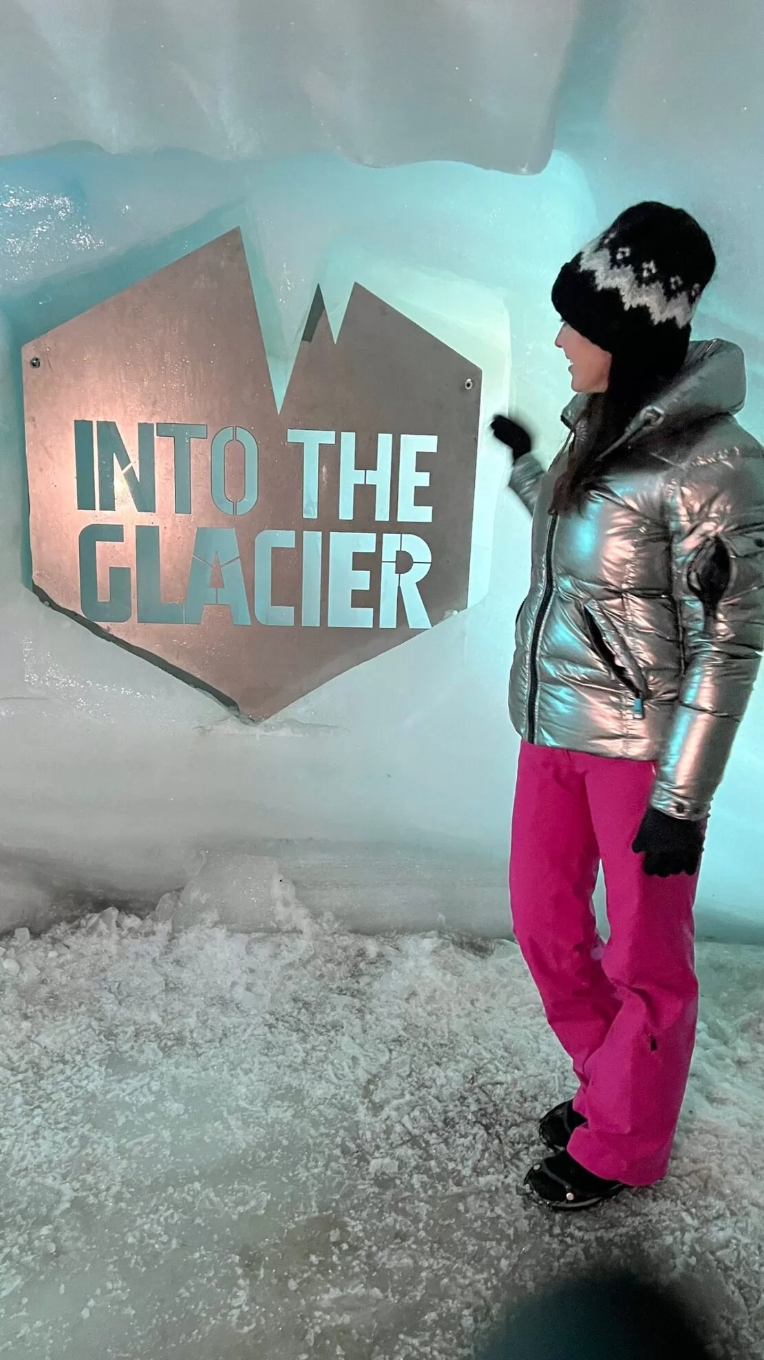 Karen Leblanc in a coat and pink pants inside into the glacier tunnel in Iceland.