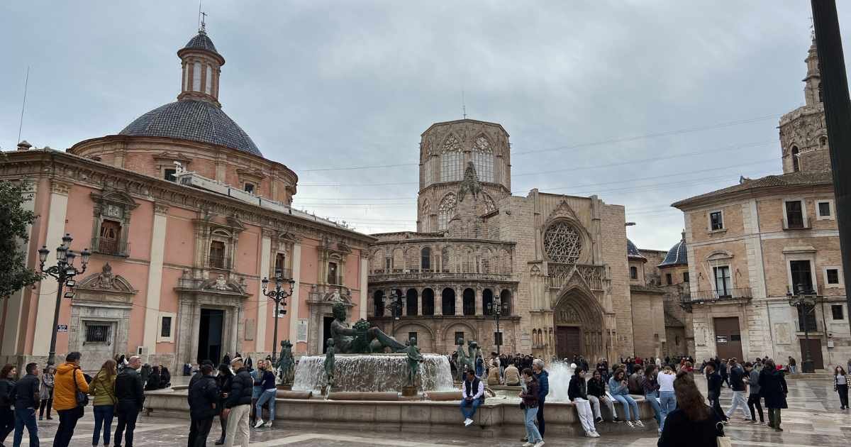 a group of people standing in front of a fountain in Plaza de la Virgen.