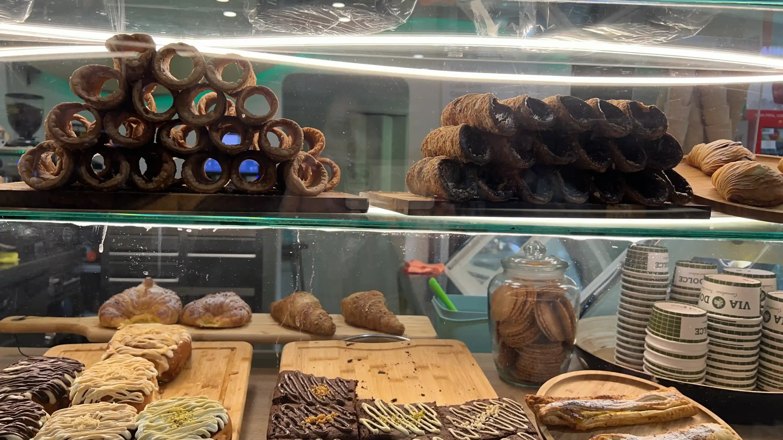 a display case with pastries and cookies in Via Dolce Cannoleria