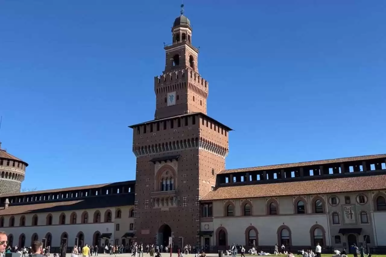 A large building of Sforza Castle with many people visiting it as tourist attraction in Milan Italy.