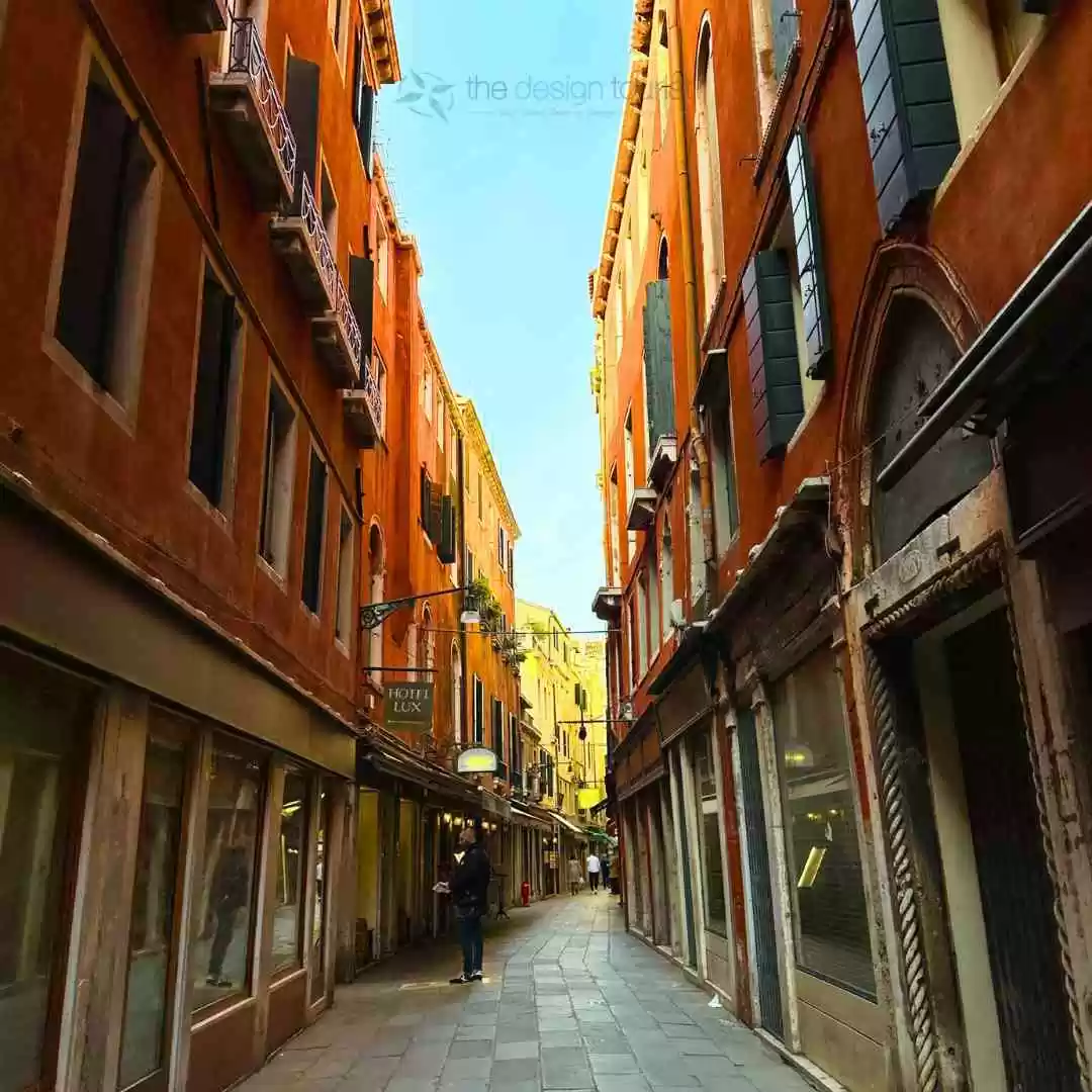 7 Must-Do Activities in Venice, Italy for an Unforgettable Trip a person walking down a narrow venice pedestrian streets.