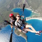 a man and woman paragliding over water