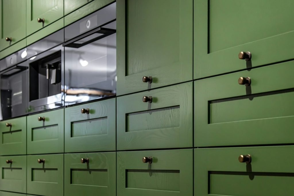 Large green kitchen cabinet with many handles, close-up.