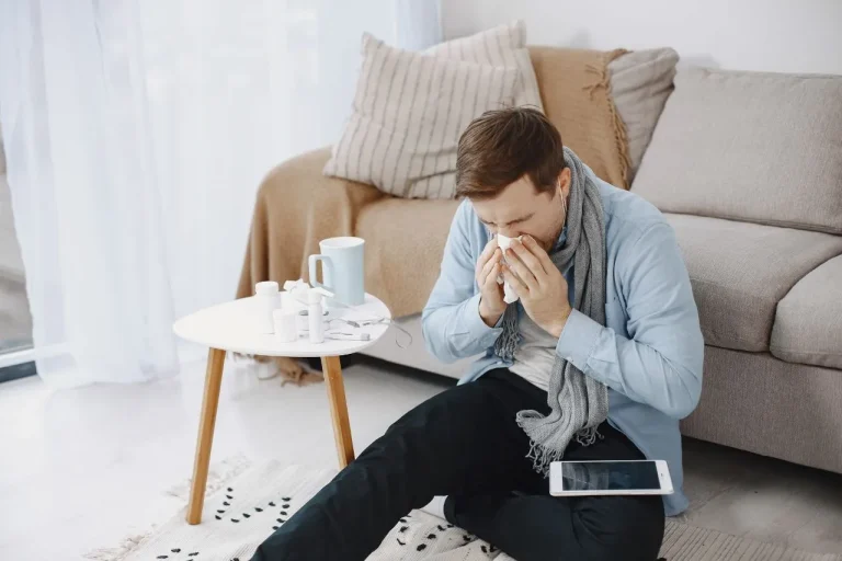 A sick man sitting on the floor in front of a coffee table.