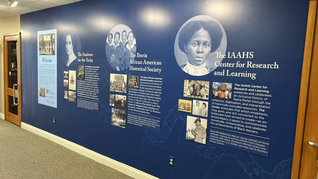 A blue Exhibit Welcome Wall with a bunch of pictures on it