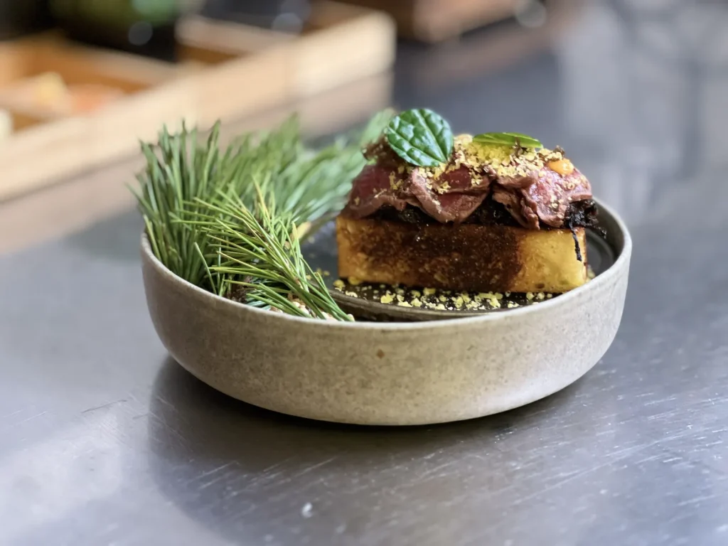 Horse Tataki dish in a plate with green garnish.