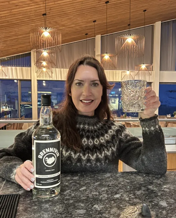 Karen holding a Brenninvin local drink in Hotel Husafell, Iceland.