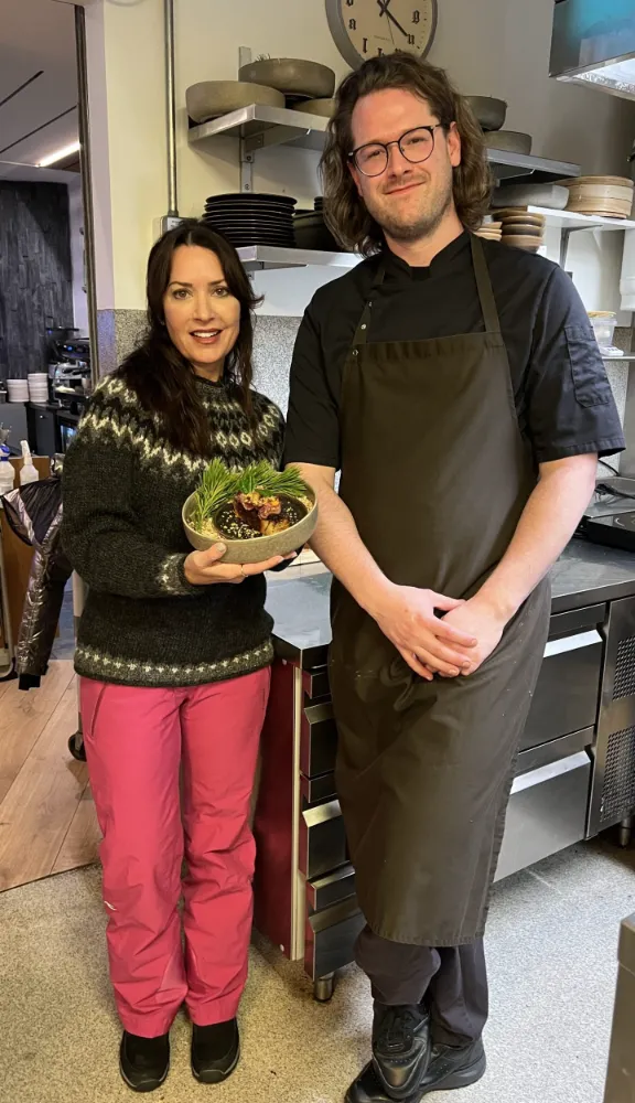 Karen holding a horse tataki dish in a plate with Chef Inigo.