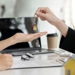 A home rental company agent is handing the house keys to a customer