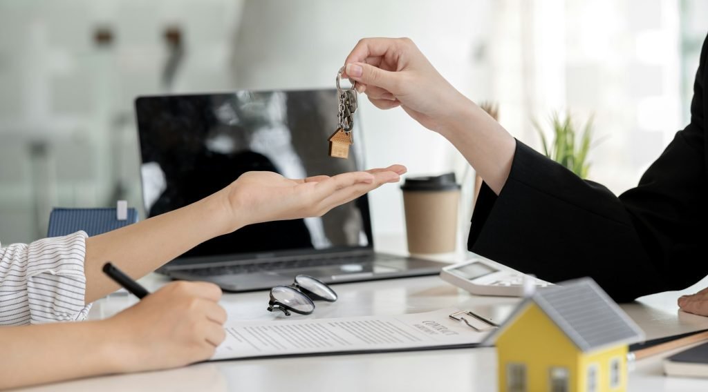 A home rental company agent is handing the house keys to a customer
