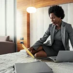 A woman in bed dressed in business attire on her business travel.