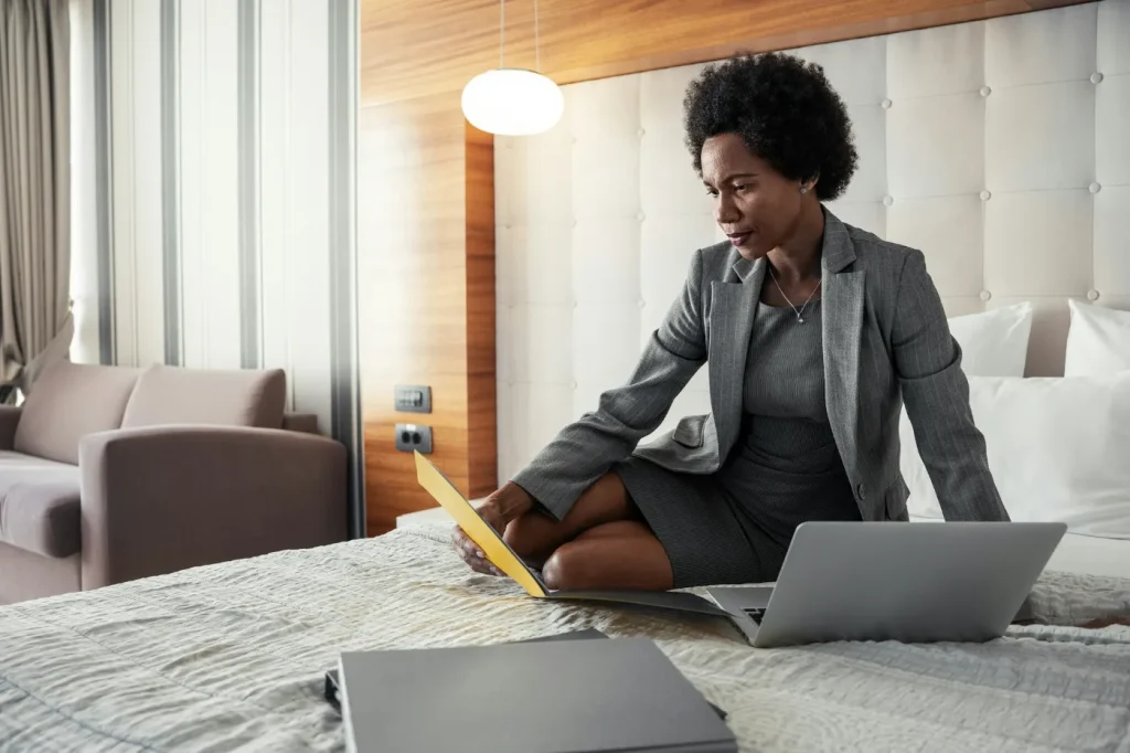 A woman in bed dressed in business attire on her business travel.