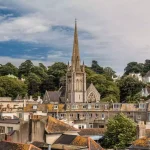 A view of a city with a steeple in the background, one of the historic cities in England.