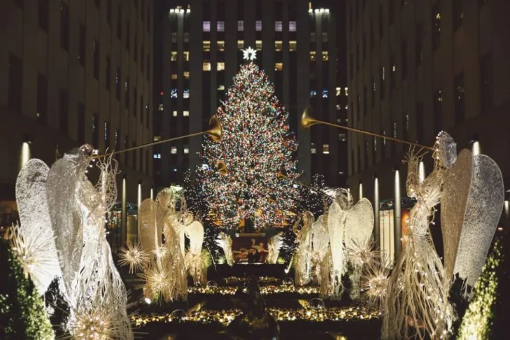 a large christmas tree surrounded by angel statues in nyc