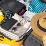 Flat lay composition with packed suitcase and travel accessories