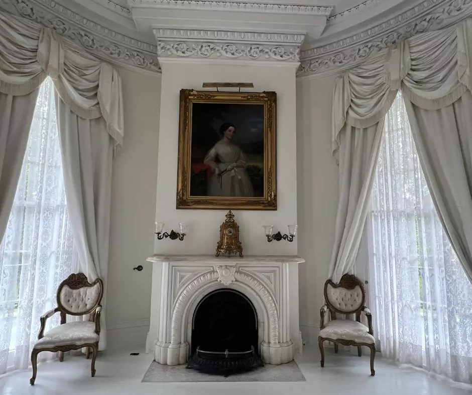a room with a fireplace and chairs of Nottoway Mansion