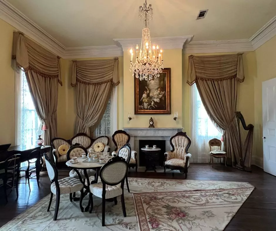a room with a chandelier and a table of Nottoway Mansion