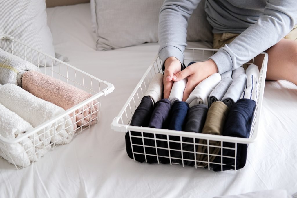 Closeup of hands of an man tidy up things in mesh storage containers. Vertical storage of clothing.