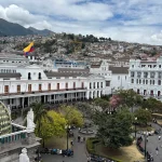 a large white building with a yellow and red flag on top of it in Quito. Is Quito safe for tourist?