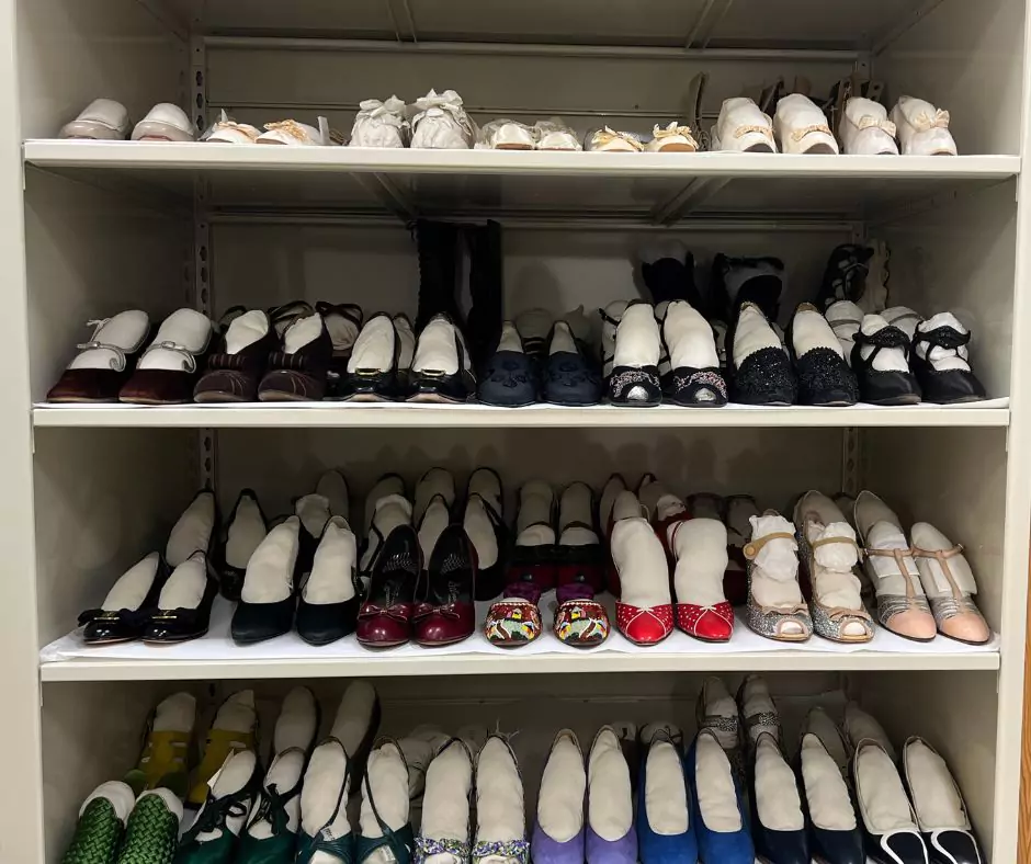 A neatly organized archive of vintage shoes, displaying a variety of heels, flats, and embellished footwear from different decades. Many shoes are stuffed with protective inserts for preservation.