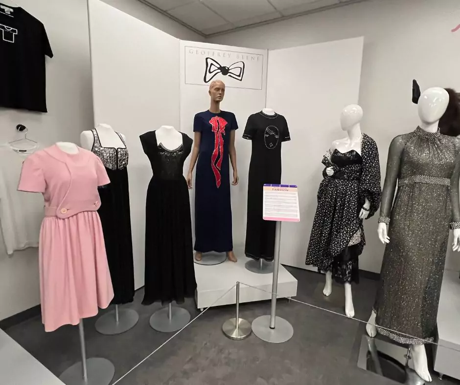 An exhibition section dedicated to Geoffrey Beene’s elegant black and pastel evening gowns. Mannequins display dresses with intricate details such as sequin embellishments, lace accents, and sculptural silhouettes.