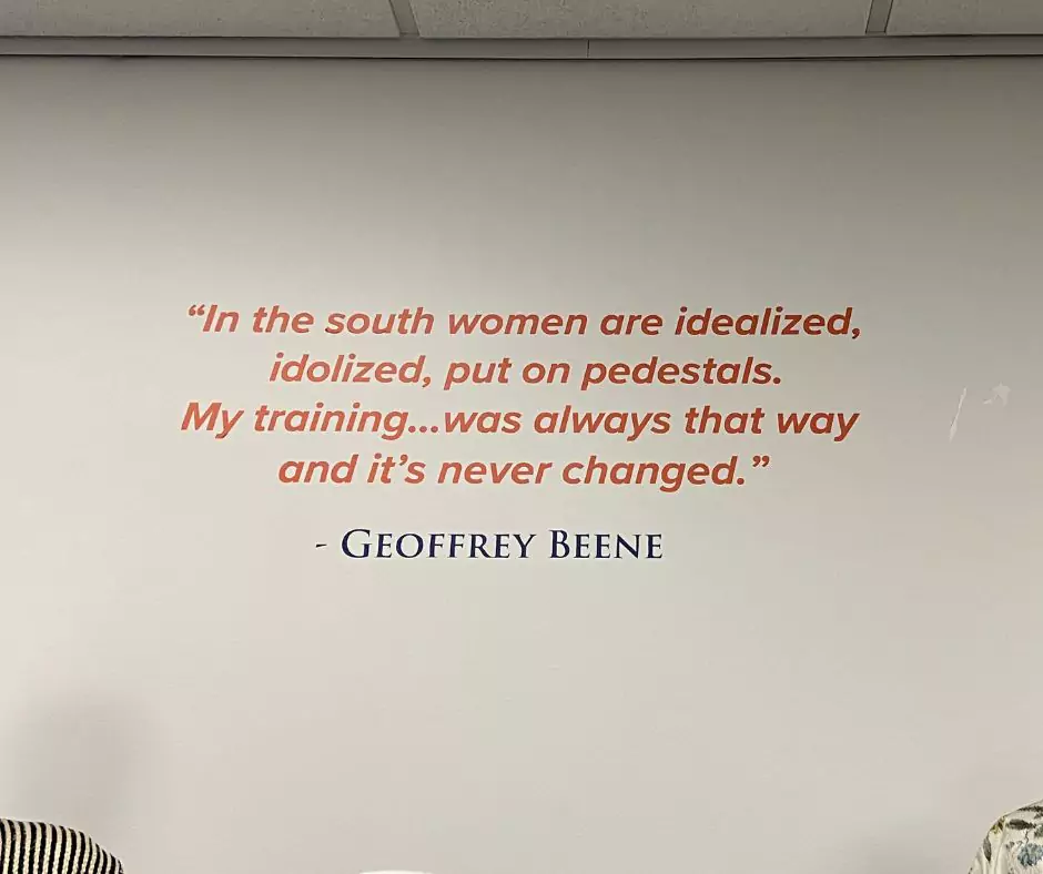 A museum wall featuring a Geoffrey Beene quote in red and blue text: “In the south women are idealized, idolized, put on pedestals. My training… was always that way and it’s never changed.” The display reflects Beene’s design philosophy.