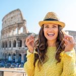 a woman listening to WeGoTrip AI Audio Tour in front of the colosseum in rome, italy