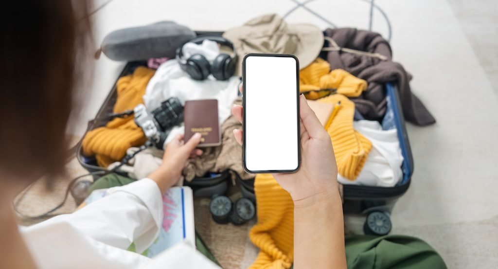 Woman prepare travel clothes using telephone screen blank mockup