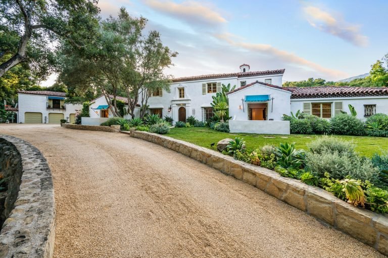 a driveway in front of a home with lots of landscaping