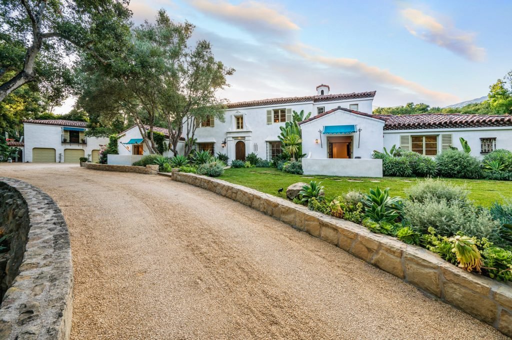 a driveway in front of a home with lots of landscaping