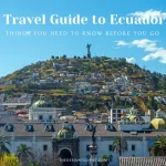 Scenic view of Quito, Ecuador with colonial architecture in the foreground and the Virgin of El Panecillo statue atop a hill surrounded by colorful hillside homes under a bright blue sky. Text overlay reads "Travel Guide to Ecuador – Things You Need to Know Before You Go."