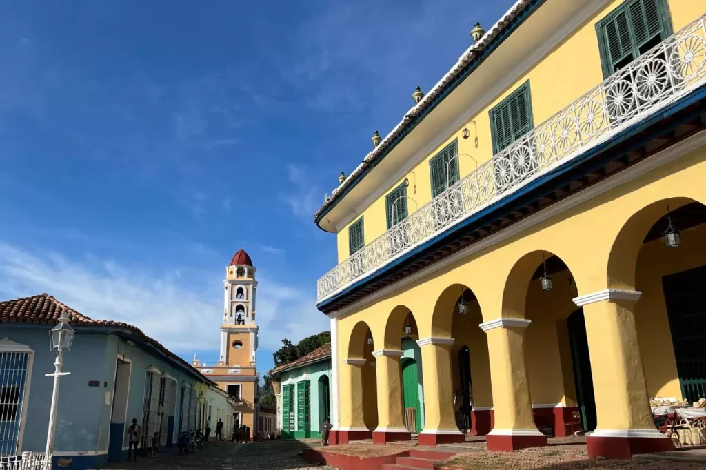 Colonial architecture in Trinidad, Cuba with vibrant buildings and bell tower, showcasing top sights and things to do in Trinidad Cuba under a sunny blue sky.