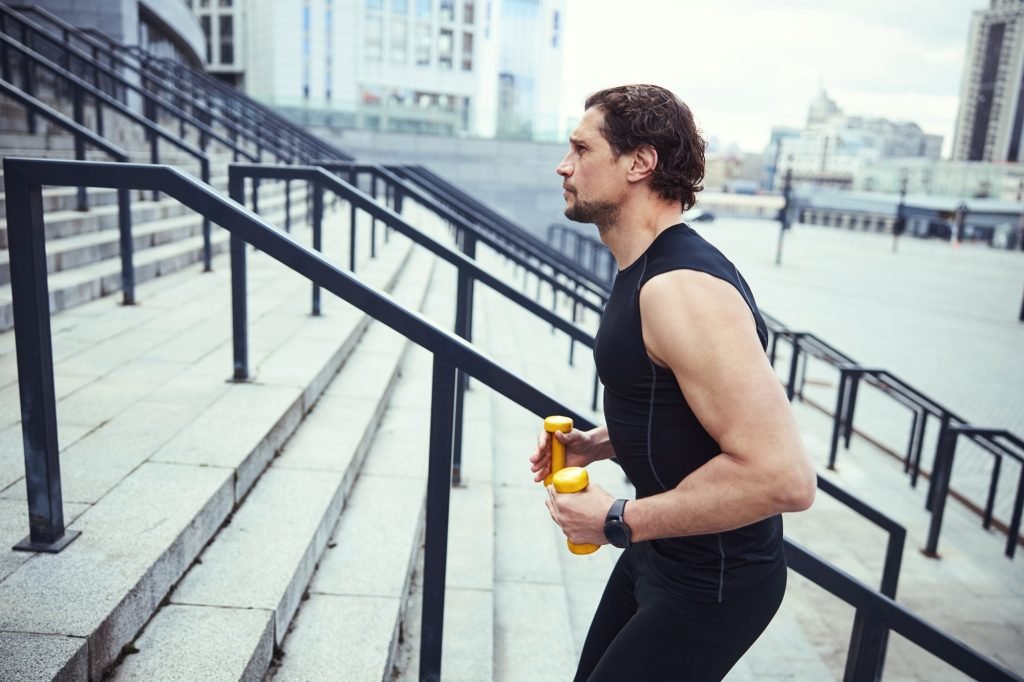 Sporty brunette male person doing workout outdoors
